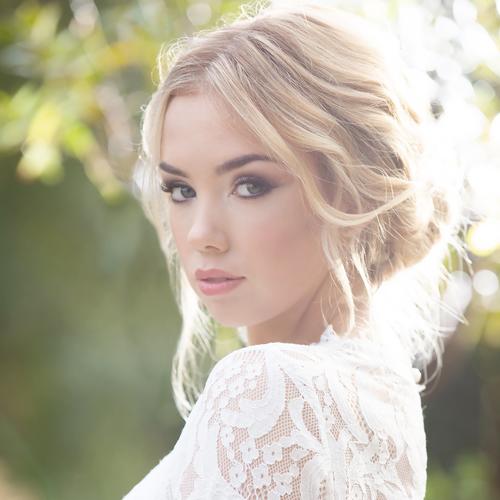 Model wearing a lacy dress with a relaxed updo and smokey eyes